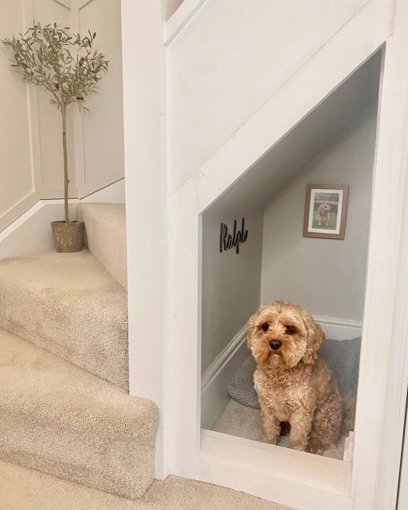 built-in dog bed under stairs with personalized name sign and dog portrait