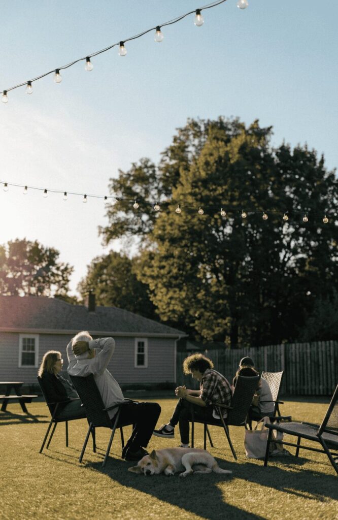 Family relaxing in a backyard with artificial turf and dog