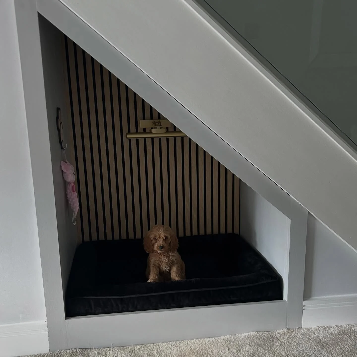modern under stair dog nook featuring oak slat panels and dark velvet mattress