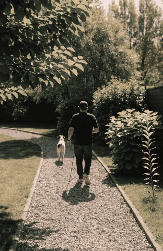 A person walking their dog along a backyard gravel path