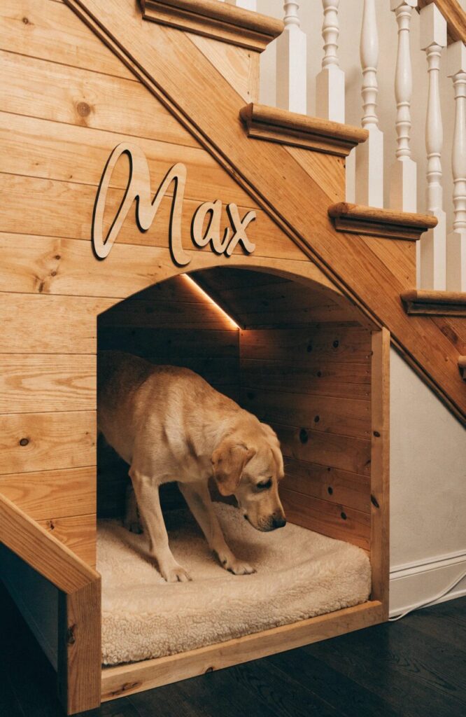 built in under stairs dog den with warm lighting and wood paneling