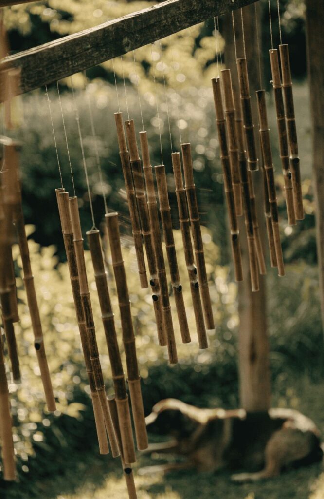 wooden wind chimes hanging in a calming backyard garden for dogs