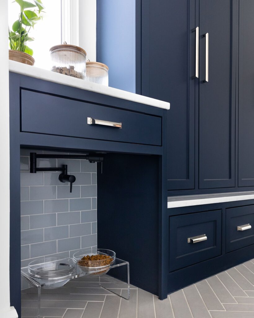 Acrylic dog bowl stand built into navy mudroom cabinetry nook