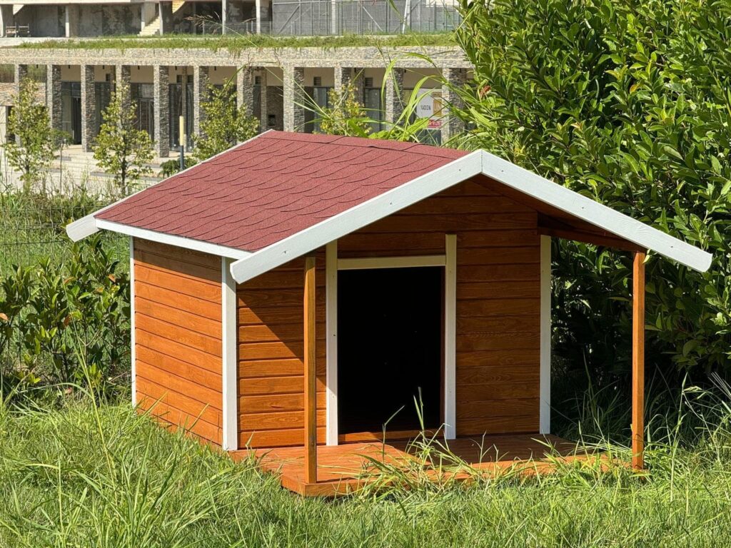 Classic wooden dog house with red shingle roof and porch