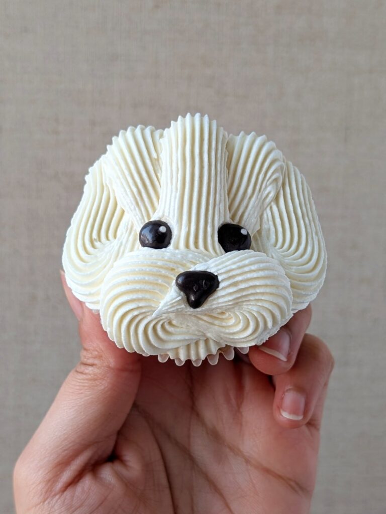 Close up of puppy face cupcake held in hand