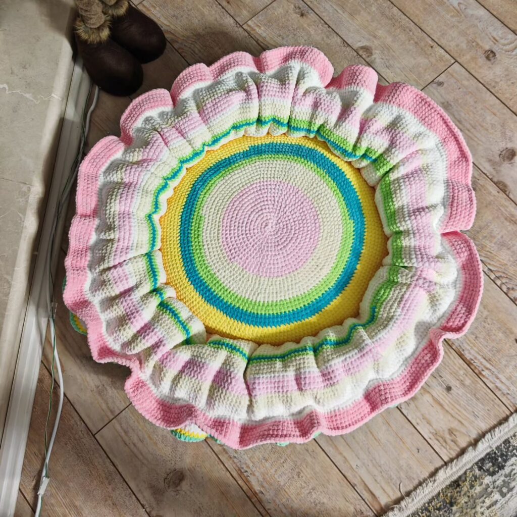 Top view of a striped ruffled crochet dog bed