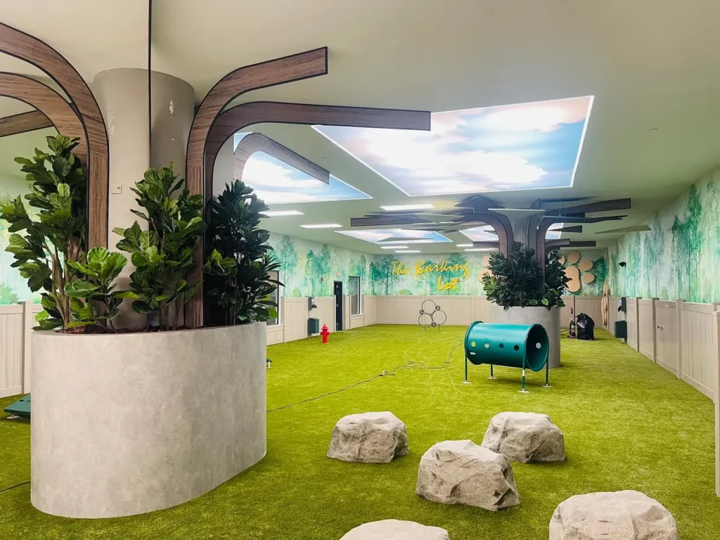 Nature themed indoor dog play room with greenery and turf